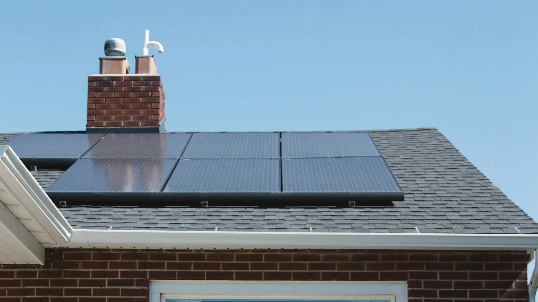 A modest brick home with solar panels installed on the roof